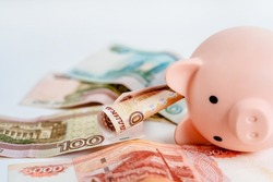 Piggy bank and Russian banknotes on a white background. The concept of accumulation and storage of money