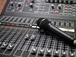 microphone rests on an audio mixer controller in the control room, Sound mixer control for live music and studio equipment, Quality audio system for professionals, music equipment concept