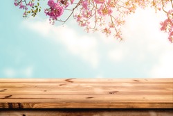 Top of wood table with pink cherry blossom flower on sky background - Empty ready for your product display or montage. 