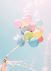 Girl hand holding colorful balloons. happy birthday party. vintage pastel filter effect