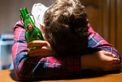 young drunk man with glass and bottle of alcohol lying on the table 