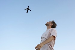 man looking up in the sky and cheer the airplane 