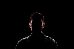 isolated dark male silhouette in the shadow, studio portrait