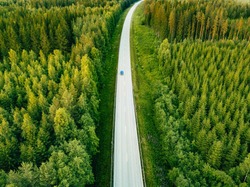 Aerial view from above of country road through the green summer forest in summer Finland. drone photography