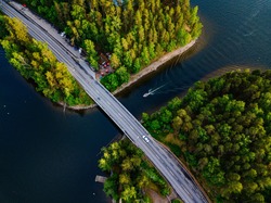 Aerial view of the bridge with a boat passing under it. Blue lake with summer houses in rural Finland.