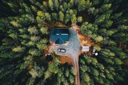 Aerial view of secluded cottage in the woods. Log cabin in the forest in rural Finland. View from above.