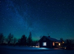 Cottage against the night sky with the Milky Way and the arctic Northern lights Aurora Borealis in snow winter Finland, Lapland