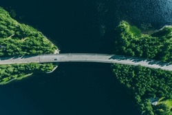 Aerial view of bridge road through blue lakes with green woods in summer Finland.