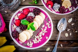 Healthy breakfast bowl: blueberry smoothie with banana, raspberry, pitaya, blackberry, almonds, sunflower and chia seeds