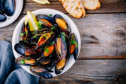 Delicious seafood mussels with with sauce and parsley.  Lemon and baguette . Clams in the shells.  Top view. 