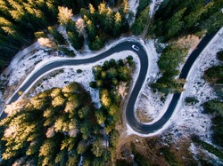 Aerial view of snowy forest with a road. Captured from above with a drone. Dolomites - Italy