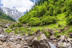 Trekkers with backpack traversing Rupin pass trail, It is full of diversity from majestic Himalayan ranges to waterfalls, glacial meadows, snow-covered landscape, lush forests.