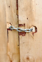 Chains keep a wooden door closed, detail of a rustic door, typical of improvised constructions