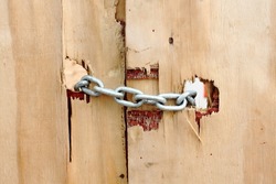 Chains keep a wooden door closed, detail of a rustic door, typical of improvised constructions