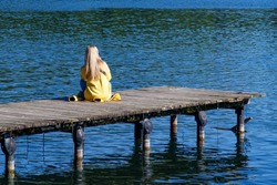 Alone. Sitting On The Pier. The girl sits alone