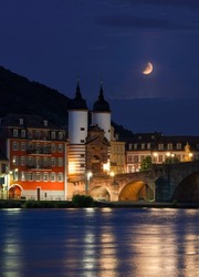 Lunar Eclipse with the old city of Heidelberg in the foreground. (16.05.2022) The full moon in earth's shadow. The old bridge and colourful buildings.