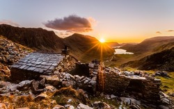 Warnscale Bothy Sunset with a sun beam and Buttermere Lake in the background.  This bothy is made from natural slate mined within the Lake District National Park, England.