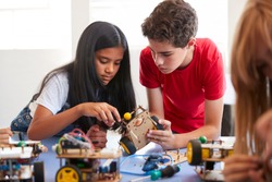 Two Students In After School Computer Coding Class Building And Learning To Program Robot Vehicle