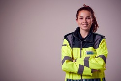 Studio Portrait Of Smiling Young Female Paramedic Against Plain Background