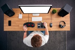 Overhead View Of Male Video Editor Working At Computer In Creative Office