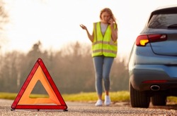 Hazard Warning Triangle Sign For Car Breakdown On Road With Woman Calling For Help