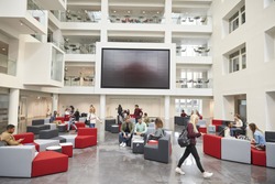 Students in front of screen in atrium of modern university