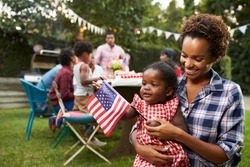 Black mother and baby holding flag at 4th July garden party