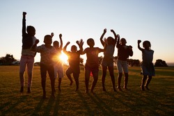Silhouetted school kids jumping outdoors at sunset