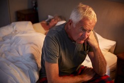 Worried Senior Man In Bed At Night Suffering With Insomnia