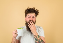Sleepy man holds cup of coffee. Yawning man holds mug with hot drink.Man with cup of fresh coffee. Tired guy hold coffee mug. Morning refreshment. Man with sleepy face try to awake with cup of coffee.