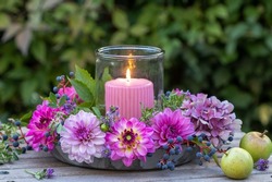 romantic arrangement with pink and purple dahlias and candle in garden