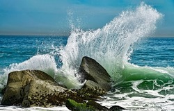 Splashes of waves break on the rocks. Sea surf on the beach. Power of water on sea surf. Splashes of sea waves