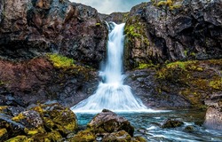 View of the waterfall in the mountains. Waterfall on mossy rocks. Mountain waterfall view. Waterfall view
