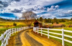 Fence road on rural landscape. Picturesque rural fence road over a covered bridge