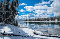 Clouds over the river in the winter snow forest. River reflection in winter snow forest. Winter river in snowy forest. Winter river landscape