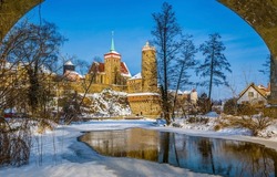 Winter castle by the snowy river. Castle on winter river in snow. Frozen river in snow at winter castle. Winter castle river landscape