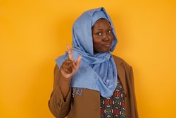 Woman gesturing a no sign. Closeup portrait unhappy, serious girl raising finger up saying: oh no you did not do that. Standing over yellow background. Negative emotions facial expressions, feelings.