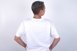 The back view of young woman with short hair wearing white t-shirt over white background Studio Shoot.