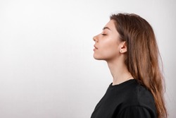 beautiful young woman on a white background stands in profile in a black shirt. copyspace. isolate