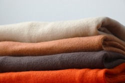 Pile or stack of fall colour, folded cashmere or merino wool jumpers.