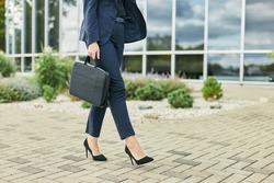 Legs detail of business woman on the way to office, walking outdoors holding a laptop case, wearing business suit and high heels, looking meet boss or colleagues, planning interview with hr manager