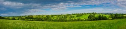 Rich, verdant, green rolling agricultural fields near Markethill in County Armagh in Northern Ireland, UK. A panoramic view taken on a sunny day in summer with light clouds.