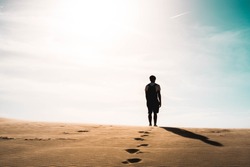 Lonely man stands in desert, footprints, sunny day