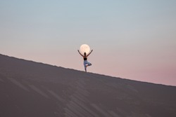 Girl doing yoga with the moon in background
