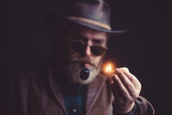 Guy smokes tobacco pipe. Hipster with beard and mustache on serious face.