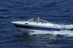 Young man driving a motor boat at ocean in the sun