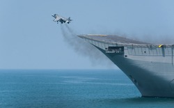 A fighter plane during a vertical take-off from an aircraft carrier at sea. A spanish navy combat plane during a war operation at sea