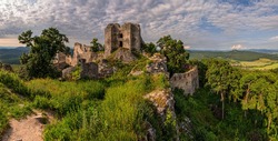 Beautiful  photo of Gymes castle ruins on hill at sunset. Vivid and colorful golden hour shot of fortress remnants from medieval age from above. Slovak cultural heritage.