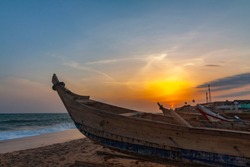 Sunset view of the beach at Cape Coast, Ghana. The ocean and wooden fishing boats on the foreground