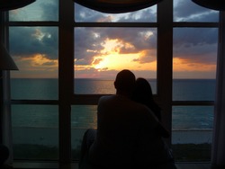 Couple watching the sunrise through a window overlooking the Atlantic Ocean in Miami Beach, Florida, spring 2011